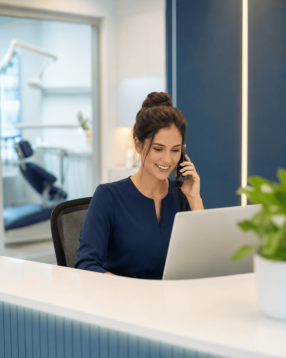 Profissional na recepção de clínica trabalhando com notebook e telefone
